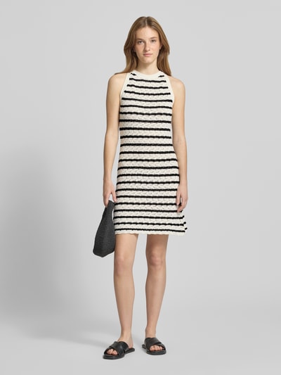 Vrouwenmodel draagt knielanges Kleid in Strick-Optik van REVIEW in zwart-wit, puur katoen, nauwsluitend, semi-transparant, mouwloos design, ronde hals, ruglengte maat S 92 cm, borstwijdte maat S 40 cm, tricotlook, volledig zichtbaar, ganzkörperansicht van voren.