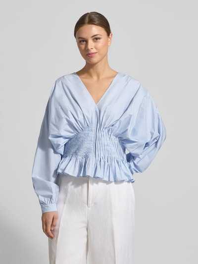 Modelka kobieca nosi Bluzka z dekoltem w serek Model 'POPLIN' od Copenhagen Muse, czysta bawełna, taliowany krój, jasnoniebieska, długość tyłu w rozmiarze S: 52 cm, długość rękawów w rozmiarze S: 70 cm, widok całej sylwetki z przodu.