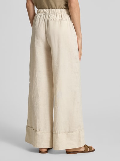 Frauenmodel trägt Leinenhose mit elastischem Bund Modell 'FLORA' von Stefanel, Wide Leg Fit, beige Farbe, reine Leinenstruktur, Ganzkörperansicht Rückansicht.