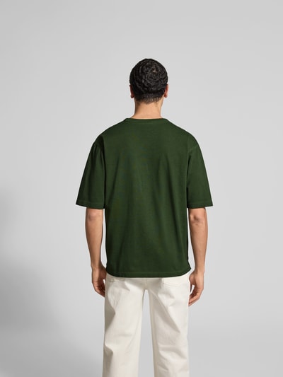 Männermodel trägt Loose Fit T-Shirt aus reiner Baumwolle von Dsquared2 in Dunkelgrün, Label-Print, kurzärmelig, Ganzkörperansicht Rückansicht.