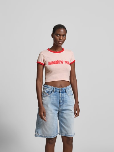Frauenmodel trägt Cropped T-Shirt aus reiner Baumwolle von Kenzo, Slim Fit, Rundhalsausschnitt, Statement-Print, Rückenlänge 40 cm, Ganzkörperansicht von vorne.
