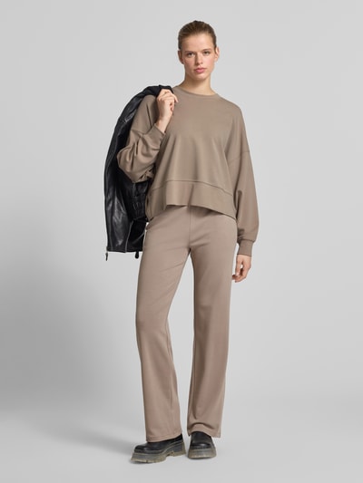 Frauenmodel trägt Oversized Sweatshirt mit breitem Bund von Juvia in Beige, aus elastischem Baumwoll-Modal-Mix, Ganzkörperansicht von vorne
