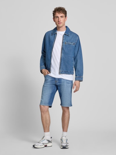Mannenmodel draagt Regular Fit Jeansshorts uit katoenmix model 'CASH' van Pepe Jeans met denimlook, vijf zakken, sierstiksels, metalen labelapplicatie en nieten, voorkant volledig zichtbaar.