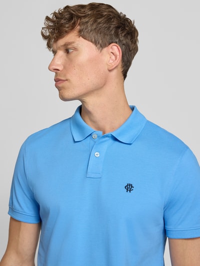 Männermodel trägt Slim Fit Poloshirt mit Label-Stitching von MCNEAL in Hellblau aus Reine Baumwolle, Knopfleiste, Nahaufnahme Oberkörper. Rückenlänge bei Größe M: 72 cm.
