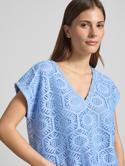 Frauenmodel trägt Boxy Fit T-Shirt mit semitransparentem Besatz Modell 'IRIS' von Vero Moda in Hellblau, abstraktes Ajour-Strickmuster, Nahaufnahme Oberkörper.