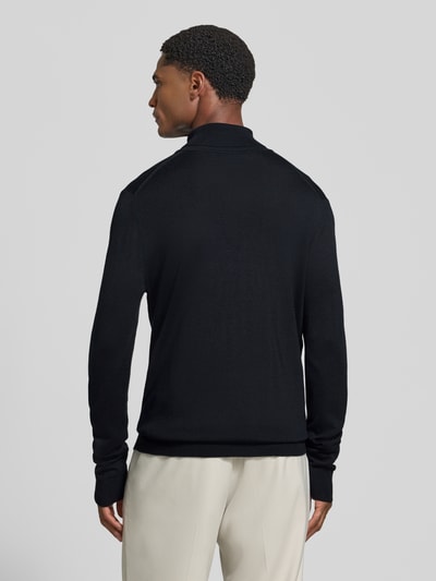 Männermodel trägt Wollpullover mit Rollkragen von Christian Berg Men in Schwarz mit gerippten Abschlüssen, Ganzkörperansicht Rückansicht.