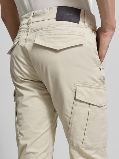 Männermodel trägt Regular Fit Cargohose aus Baumwoll-Mix von s.Oliver RED LABEL, efekt: jednolity kolor, naszywka z logo, nity, szlufki na pasek, wpuszczane kieszenie, kieszeń z tyłu, kieszenie cargo, mieszanka bawełny, krój regular fit, spodnie z prostymi nogawkami, średni stan, Ganzkörperansicht Rückansicht.