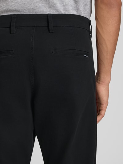 Männermodel trägt Straight Fit Hose aus Baumwoll-Mix Modell 'Kane' von JACK & JONES in Schwarz, Detailaufnahme Rückansicht, elastisches Material, Eingriff- und Gesäßtaschen, Knopf- und Reißverschluss, Bundweite 41 cm, Innenbeinlänge 77 cm.