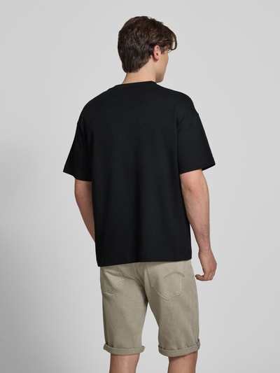 Männermodel trägt T-Shirt mit Rundhalsausschnitt Modell 'BARRON' von Jack & Jones in zwart, regular fit van katoenmix, ruglengte maat M 69 cm, Ganzkörperansicht Rückansicht.