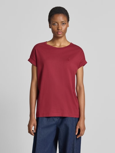 Frauenmodel trägt dunkelrotes Loose Fit T-Shirt aus reiner Baumwolle Modell 'IDAARA' von ARMEDANGELS, kombiniert mit blauer Hose, Ganzkörperansicht von vorne. Damen T-Shirt von ARMEDANGELS.