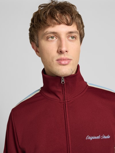 Männermodel trägt Sweatjacke mit Stehkragen Modell 'COTEDAZUR' von Jack & Jones in Bordeaux mit Label-Stitching, Nahaufnahme Oberkörper.