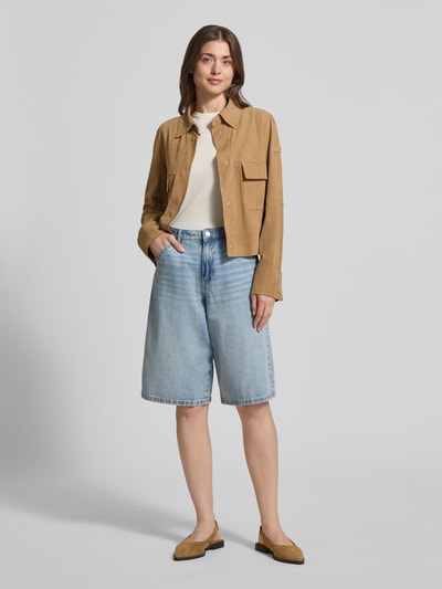 Frauenmodel trägt Lederjacke mit Pattentaschen Modell 'Era' von Peuterey in Beige, kombiniert mit hellblauer Jeansbermuda, glatter Stoff, Ganzkörperansicht von vorne.
