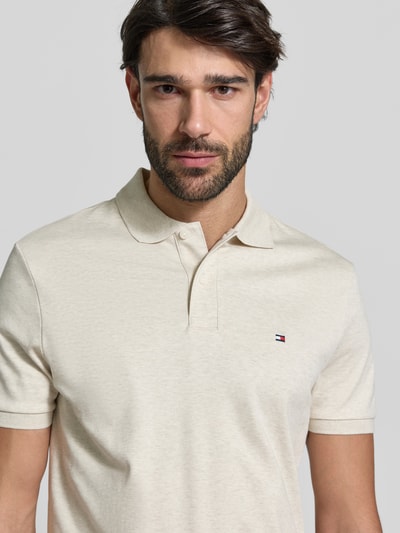 Männermodel trägt Regular Fit Poloshirt aus reiner Baumwolle Modell 'LIQUID COTTON' von Tommy Hilfiger in Melange-Optik, Nahaufnahme Oberkörper.