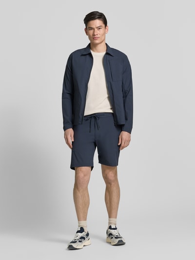 Männermodel trägt Straight Fit Shorts mit Eingrifftaschen Modell 'Drift' von SCANDINAVIAN EDITION in Dunkelblau, elastischer Bund, Ganzkörperansicht von vorne.