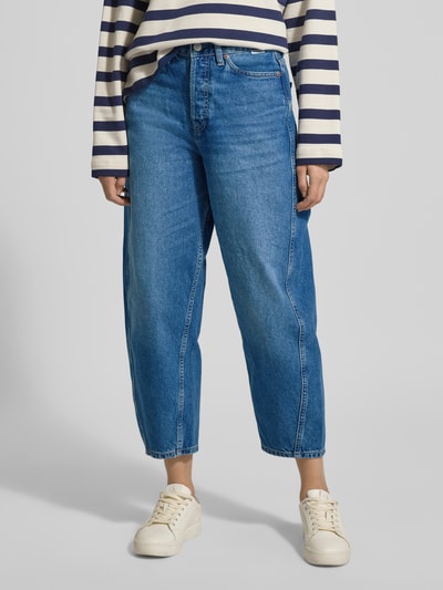 Frauenmodel trägt High Waist Barrel Jeans aus reiner Baumwolle Modell 'BAARLY' von Armedangels in Denim-Optik, 5-Pocket-Design, Label-Patch, Nieten, Knopf und verdeckter Reißverschluss, Ankle-Länge, Ganzkörperansicht von vorne.