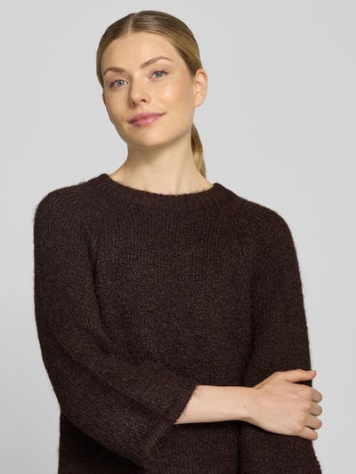 Vrouwenmodel draagt gebreide pullover met Raglanmouwen van FREE/QUENT in donkeren tinten, materiaalmix met wol, recht model, ronde hals, ruglengte maat S 54 cm, mouwlengte maat S 50 cm, Nahaufnahme Oberkörper.