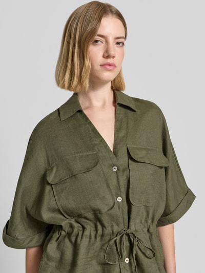 Frauenmodel trägt Relaxed Fit Leinenbluse mit Brusttaschen von Christian Berg Woman in Olivgrün, Knopfleiste, Hemdblusenkragen, Schnürung, reine Leinen-Textur, Ärmel mit Aufschlag, Nahaufnahme Oberkörper.