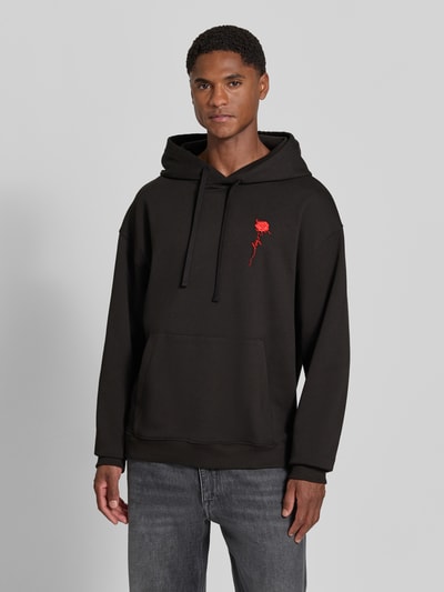 Männermodel trägt Regular Fit Hoodie aus reiner Baumwolle Modell 'Diflowhood' von HUGO in Schwarz mit rotem Detail, Ganzkörperansicht von vorne, Herren Hoodie von HUGO.