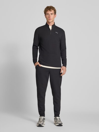 Männermodel trägt Regular Fit Sweatpants mit Lyocell-Anteil von PUMA PERFORMANCE in Schwarz mit Logo und elastischem Bund, Ganzkörperansicht von vorne.