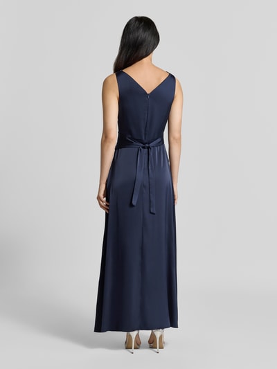 Frauenmodel trägt Abendkleid mit Wasserfallausschnitt von Rinascimento in Dunkelblau, Material-Mix mit Stretch-Anteil, taillierte Passform, geraffter Stoffgürtel, Rückansicht, Ganzkörperansicht Rückansicht.