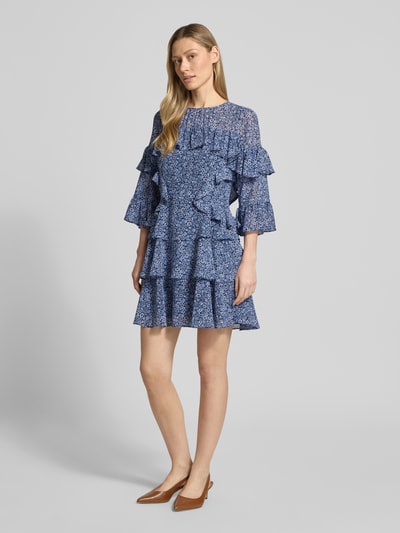 Frauenmodel trägt Minikleid mit Volants von MICHAEL Michael Kors in Blau, A-Linie, Allover-Look, Rundhalsausschnitt; Ganzkörperansicht von vorne, Rückenlänge bei Größe S: 86 cm, Brustweite bei Größe S: 44 cm, Ärmellänge bei Größe S: 32 cm.