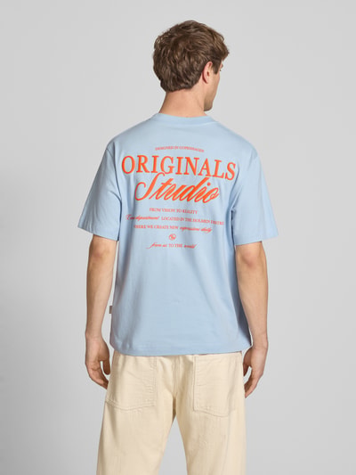 Männermodel trägt T-Shirt mit Label-Print von Jack & Jones in Hellblau, Relaxed Fit, reine Baumwolle, Rundhalsausschnitt, Ganzkörperansicht Rückansicht.