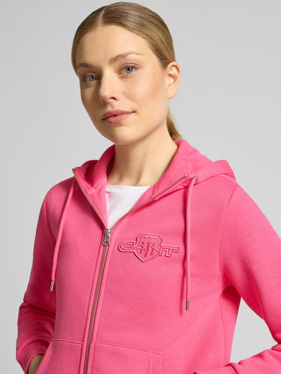 Frauenmodel trägt Sweatjacke mit Zweiwege-Reißverschluss und Label-Patch von Gant aus Baumwoll-Elasthan-Mix, Regular-Fit, Kapuze, Känguru-Tasche, Nahaufnahme Oberkörper.