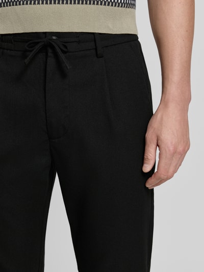 Männermodel trägt Slim Fit Stoffhose mit Viskose-Anteil von Lindbergh, Schwarz, Elastischer-Material-Mix, Strukturmuster, Nahaufnahme Oberkörper.