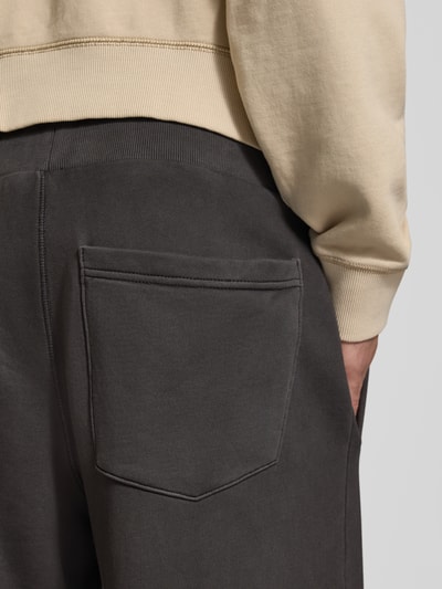 Männermodel trägt Relaxed Fit Sweathose aus reiner Baumwolle von G-Star RAW in Dunkelgrau, glatte Textur, Nahaufnahme Rückansicht.