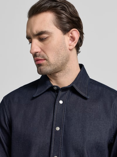 Männermodel trägt Oversized Hemdjacke aus Baumwoll-Mix Modell 'LIAM' von BOSS, unifarben, Denim-Textur, Nahaufnahme Oberkörper.