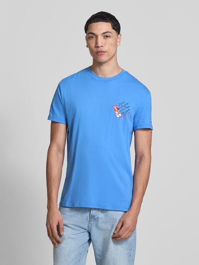 Männermodel trägt Regular Fit T-Shirt aus reiner Baumwolle von Tommy Jeans in Unifarben, Label Print, Jersey, Ganzkörperansicht von vorne.