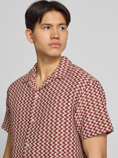 Mannelijk model draagt Regular Fit Freizeithemd im Allover-Look Modell 'MONTAUK' van Jack & Jones, beige-rood dessin, katoenmix, reverskraag, knoopsluiting, schouderbreedte 50 cm, mouwlengte 22 cm, ruglengte 71 cm, close-up bovenlichaam.