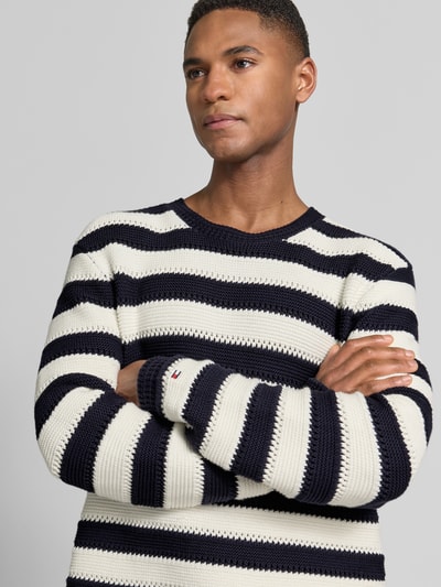Männermodel trägt Regular Fit Strickpullover aus reiner Baumwolle von Tommy Hilfiger, Optik:Allover-Muster, Gestreift, Nahaufnahme Oberkörper.