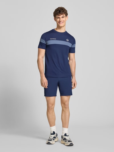 Männermodel trägt Shorts mit Logo-Print Modell 'GOCCIA' von SERGIO TACCHINI in Dunkelblau, Material-Mix, lockerer Schnitt, Ganzkörperansicht von vorne.