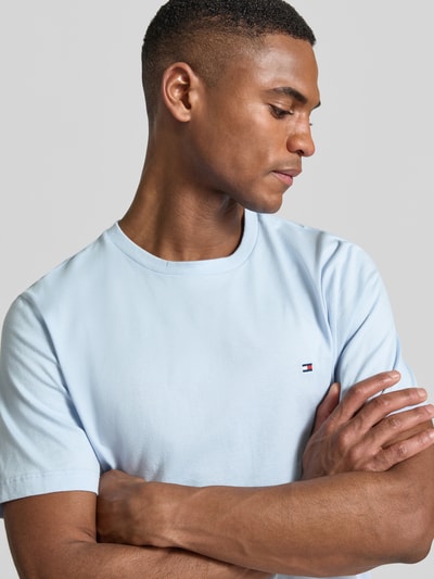 Męski model nosi Regular Fit T-Shirt aus reiner Baumwolle von Tommy Hilfiger, efekt: jednolity kolor, krój regular fit, wyhaftowane logo, okrągły dekolt, krótki rękaw, wykończenie materiału: dżersej, bawełna, jasnoniebieski, zbliżenie na górną część ciała.