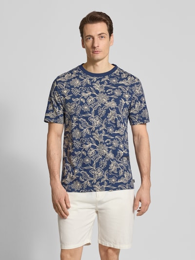 Männermodel trägt T-Shirt im Allover-Look mit Rundhalsausschnitt von Scotch & Soda, Reine Baumwolle, Regular-Fit, Ganzkörperansicht von vorne.