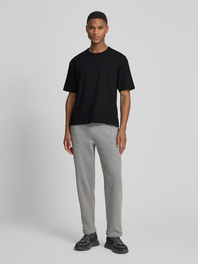 Männermodel trägt Cropped T-Shirt mit Rundhalsausschnitt von GAP aus reiner Baumwolle, schwarz, Ganzkörperansicht von vorne.