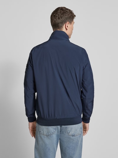 Männermodel trägt Windbreaker mit Stehkragen Modell 'YETUR' von CARS JEANS in Dunkelblau, glatte Struktur, Ganzkörperansicht Rückansicht. Material-Mix mit Stretch-Anteil, gerader Schnitt, elastische Abschlüsse, Reißverschlusstasche am Arm.