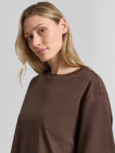 Vrouwenmodel draagt T-shirt met ronde hals model 'PINARA' van Drykorn in bruin, puur katoen, relaxed fit, ruglengte maat S 58 cm, detailopname.