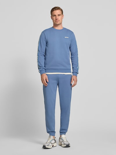 Männermodel trägt Sweatshirt mit Label-Patch und Rundhalsausschnitt von EA7 Emporio Armani, blauer Baumwoll-Mix, Loose-Fit, Ganzkörperansicht von vorne. Rückenlänge bei Größe M 67 cm, Ärmellänge 68 cm.