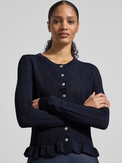 Vrouwenmodel draagt Strickjacke mit Rundhalsausschnitt und Wellensaum van Christian Berg Woman Selection, materiaalmix met viscose, regular fit, ronde hals, knoopsluiting, golvende zoom, ruglengte 53 cm maat 36, mouwlengte 67 cm maat 36, donkerblauw, textuur grof gebreid, nahaufnahme bovenlichaam.