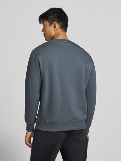 Männermodel trägt Sweatshirt mit Label-Details von Alpha Industries aus Baumwoll-Mix mit gerippten Abschlüssen, Ganzkörperansicht Rückansicht.