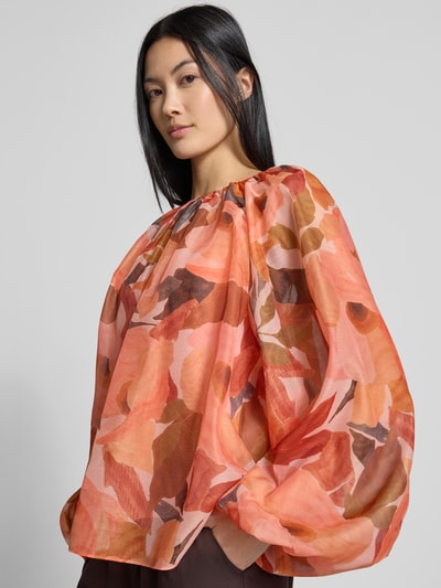 Vrouwenmodel draagt Relaxed Fit blouse met all-over bloemenprint Model 'Sabrona' van Ted Baker, plooien, met lange mouwen, ruglengte maat 36: 56 cm, mouwlengte maat 36: 74 cm, dames blouse, warme oranjerode en bruine tinten, transparante lichte stof, all-over bloemenmotief, vooraanzicht bovenlichaam.