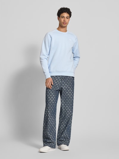 Męski model nosi Sweatshirt mit Label-Stitching od adidas Originals, jasnoniebieski, okrągły dekolt, bawełniany miks, luźny krój, ściągacze, długość tyłu 70 cm, długość rękawa 83 cm, widok całej sylwetki z przodu.
