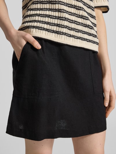 Frauenmodel trägt Minirock aus Leinen-Viskose-Mix Modell 'LINNO' von ICHI, schwarz, A-Linie, Allover-Look, elastischer Bund, Nahaufnahme Oberkörper.