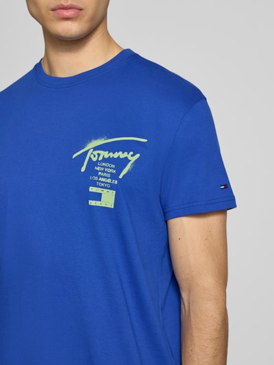 Männermodel trägt Regular Fit T-Shirt aus reiner Baumwolle von Tommy Jeans in Optik: Unifarben mit Label-Schriftzug, Rundhals, Ärmelform: Kurzarm, Materialverarbeitung: Jersey, Nahaufnahme Oberkörper.