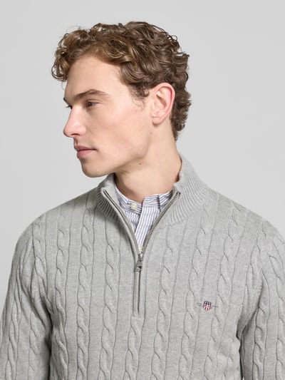 Männermodel trägt Strickpullover mit gerippten Abschlüssen von Gant aus reiner Baumwolle, Slim-Fit, Stehkragen, Label-Stitching, Nahaufnahme Oberkörper.