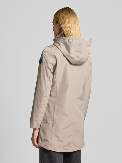 Frauenmodel trägt Regular Fit Mantel mit Logo-Applikation von NAUTGÅRD in Beige mit Kapuze, Stehkragen, Eingrifftaschen, Rückenlänge 88 cm, Ganzkörperansicht Rückansicht.