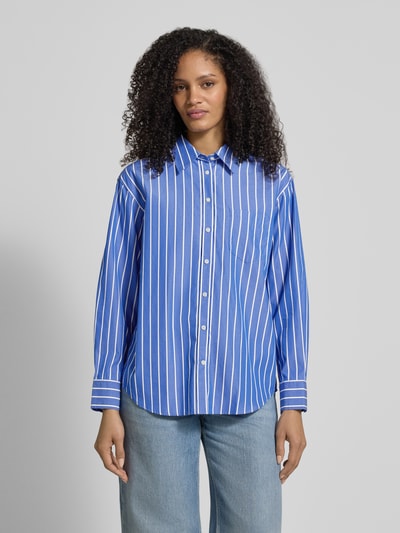 Kobiece model prezentuje Relaxed Fit Bluse mit Brusttasche od Gant, bawełna, kołnierzyk koszulowy, brustasza, listwa guzikowa, długość tyłu 70 cm, długość rękawów 62 cm, niebieskie pionowe pasy, faktura gładka, widok całej sylwetki z przodu.