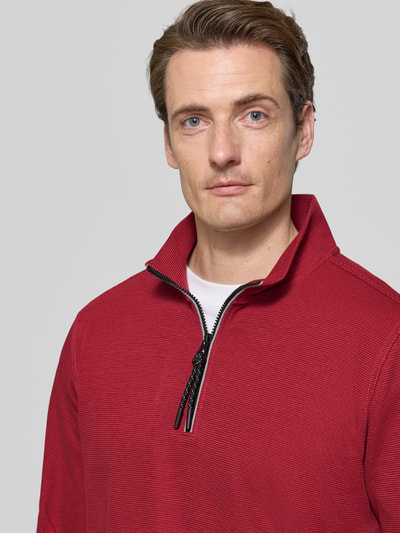 Männermodel trägt Relaxed Fit Sweatshirt aus Baumwoll-Mix Modell 'SELANIK' von LERROS in Rot mit Troyer-Kragen, Nahaufnahme Oberkörper.